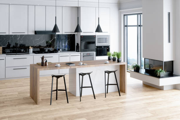 Modern kitchen interior with island, sink, cabinets, kitchen appliances and hardwood floor in a new luxury home.